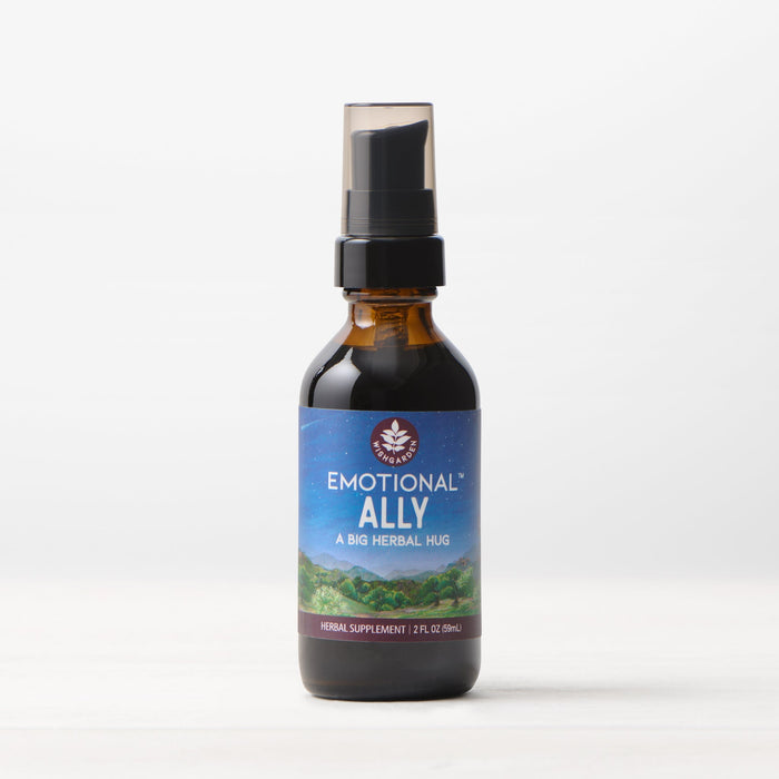 A brown glass bottle with a black spray cap labeled "Emotional Ally: A Big Herbal Hug" rests on a white surface. The label displays a scenic landscape, reflecting its mood and emotional support benefits.