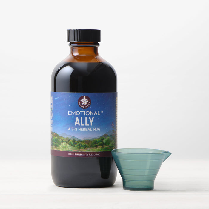 A brown bottle labeled "Emotional Ally: A Big Herbal Hug" with a small measuring cup sits on a light surface against a white background—ideal for those seeking mood support.