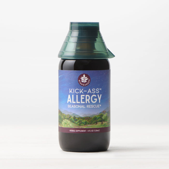 A bottle of Kick-Ass Allergy, Seasonal Rescue tincture featuring a blue and purple label with a mountain design and green cap, displayed on a light surface against a plain background.