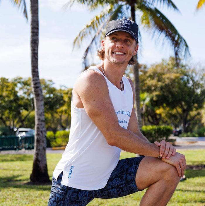 Man wearing the Core Zero Running Tank in Cheaper Than Therapy Run Club White, side view