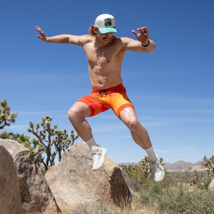 Man wearing the Flexion 8 inch Half Tights in Orange Crush, running