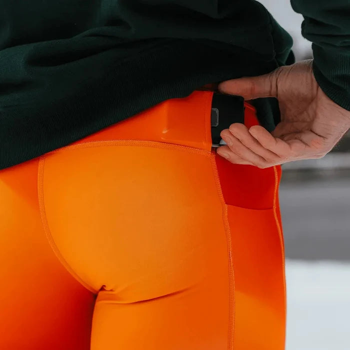 Man wearing the Flexion Max Compression Tights in Orange Crush, close-up