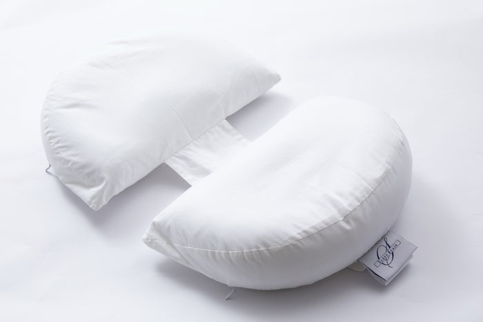 The Side Sleeping Chest Pillow, a butterfly-shaped white pillow with a curved center gap and fabric strip, is shown on a white background. A logo tag accents one side, making it ideal for post-surgery breast support.
