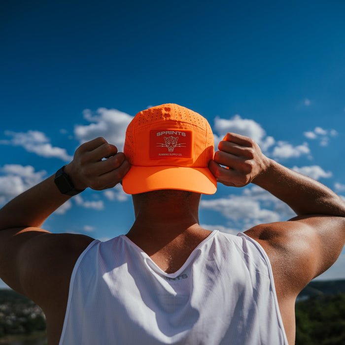 Person wearing the Out of Breath Orange HyperG Hat outdoors