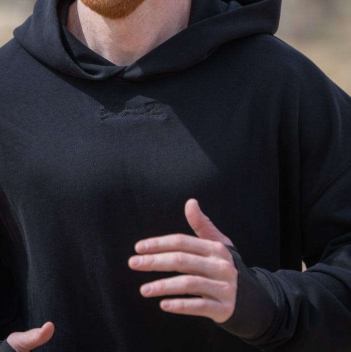 Person wearing the Run Club Oversized Hoodie in Cheaper than Therapy Black, side view