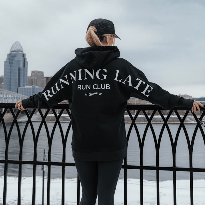 Person wearing the Run Club Oversized Hoodie in Running Late Black