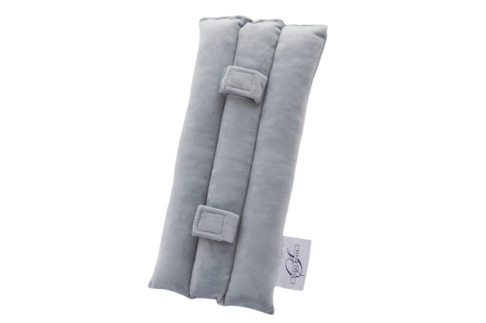 The Seat Belt Pillow is a light gray, rectangular padded fabric cushion designed for chest support. It features three cushioned sections, two rectangular fabric loops, and a small white logo tag on the side. The background is plain white.