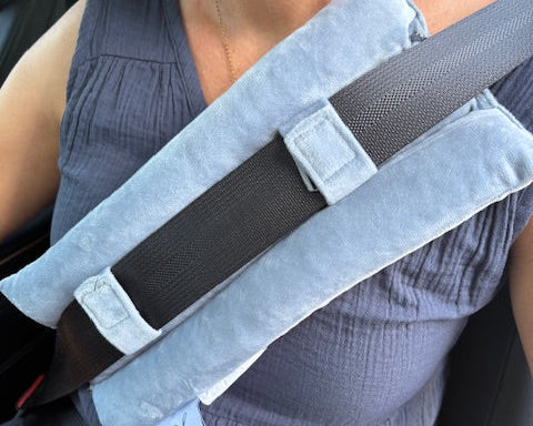 A person uses the Seat Belt Pillow, a blue cushion over a standard car seatbelt, for added comfort and chest support, reducing shoulder and chest pressure.