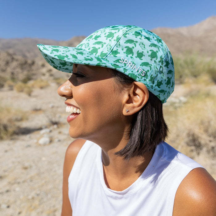 Runner wearing the Shelly's Reef Run Sea Turtle OG Hat near the ocean