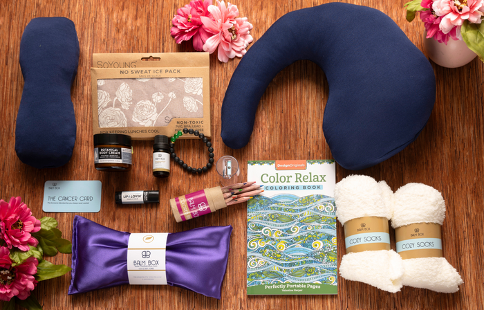 The Best Mastectomy Care Package includes a neck pillow, cozy socks, lotion, coloring book with pencils, ice pack, lavender pack, lip balm, card, and pink flowers—thoughtfully arranged for self-care after surgery.