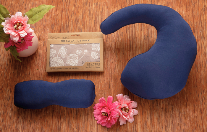 Three blue No Sweat Ice Packs in various shapes rest on wood with pink flowers, alongside a labeled box—perfect for including in The Best Mastectomy Care Package or a thoughtful breast cancer gift box.