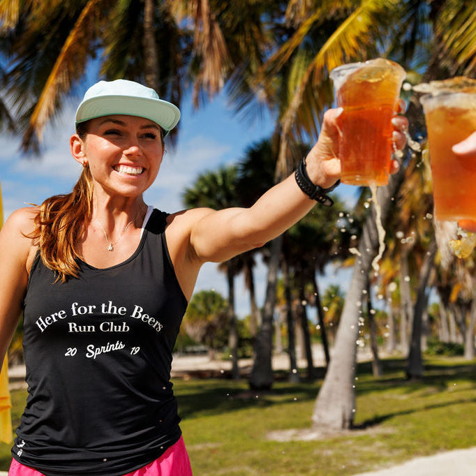 Woman wearing the Core Zero Running Tank in Here For The Beers Run Club Black