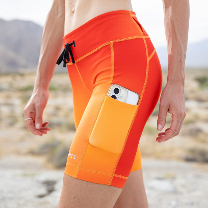 Woman wearing the Flexion 8 inch Compression Short in Orange Crush