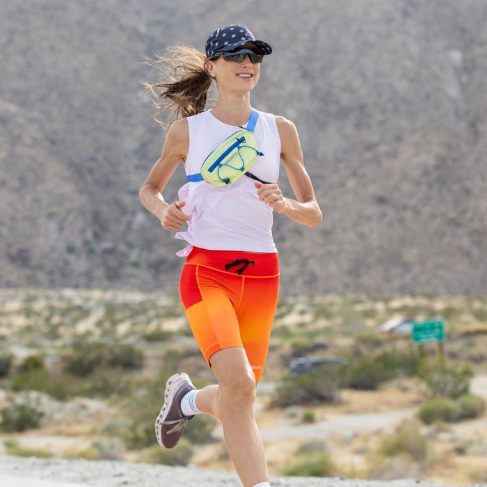 Woman wearing the Flexion 8 inch Compression Short in Orange Crush, side view